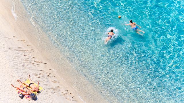 The view from above as a family sunbathes and plays in the sea